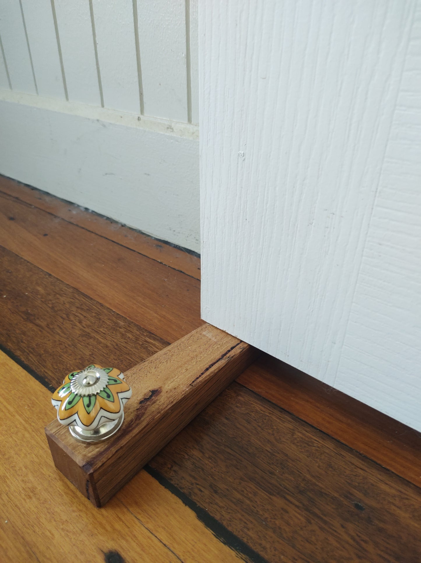 Door stop, White/Orange/Green knob on blonde timber.