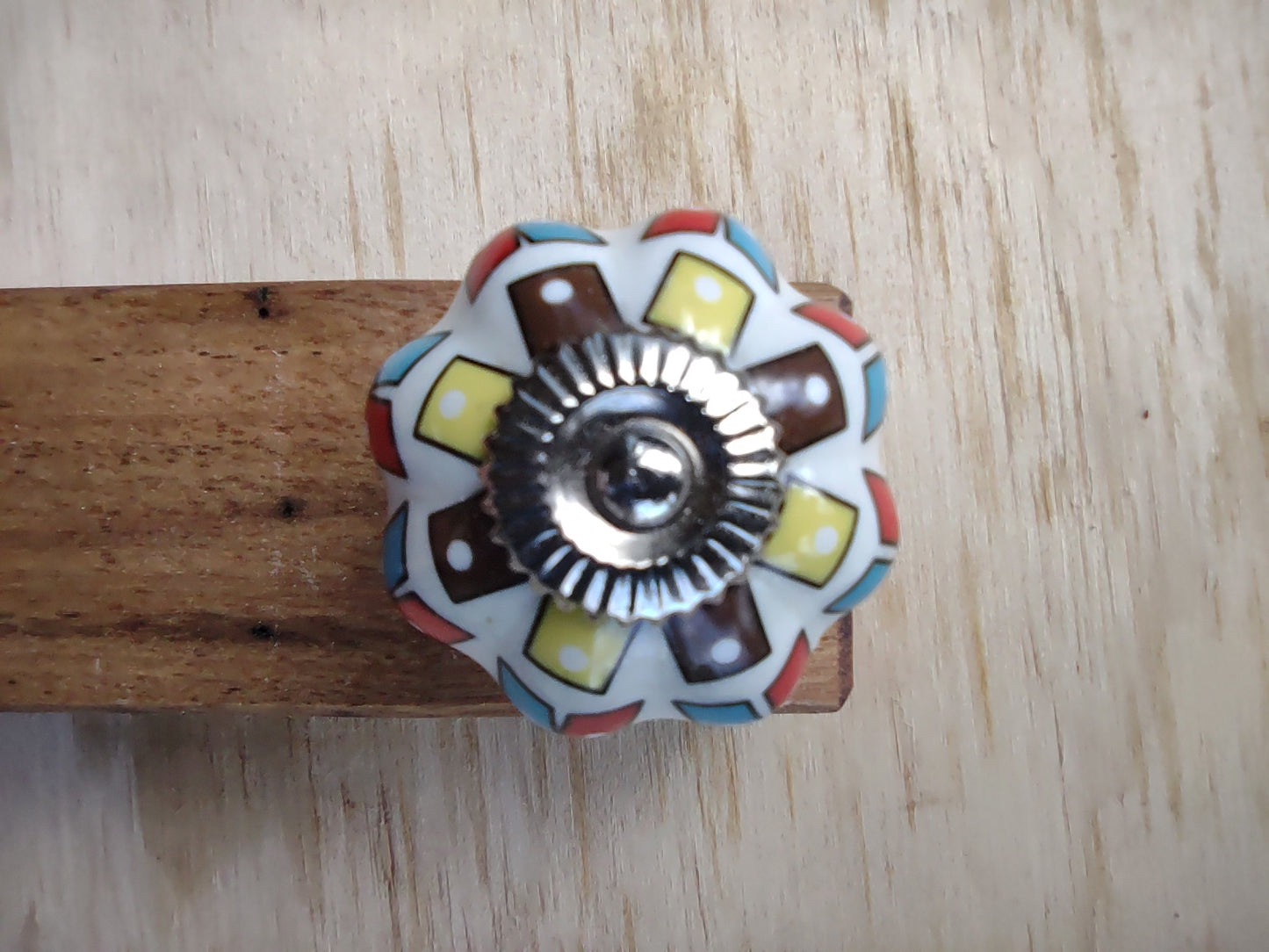 Door stop, White knob with Yellow/Brown & Red/Blue pattern on blonde timber.